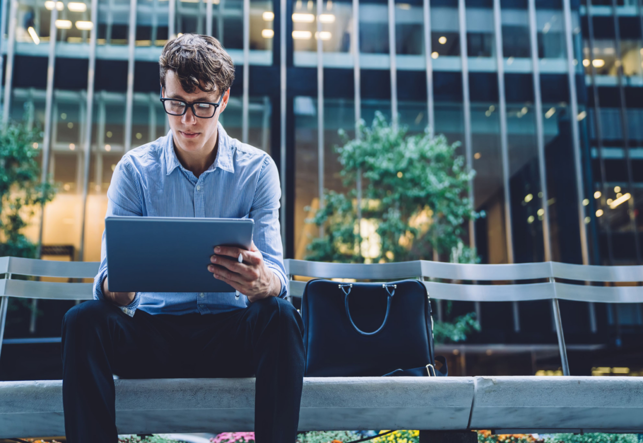 Photo of man working on a tablet outside his workplace.